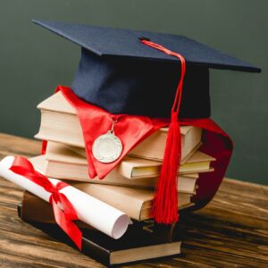 books, academic cap, medal and diploma on wooden surface isolated on grey